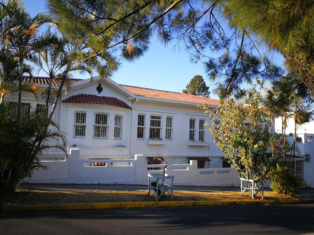 uma casa branca com duas cadeiras à frente em Costa Rica Guesthouse em San José