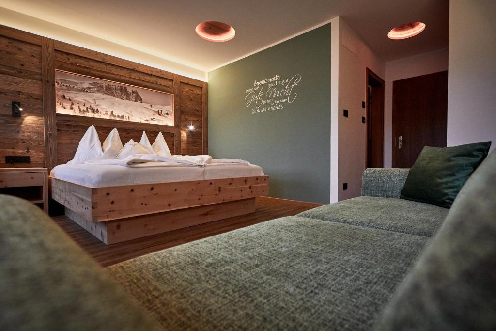 a bedroom with a bed and two chairs at Hotel Garni Savoy in Castelrotto