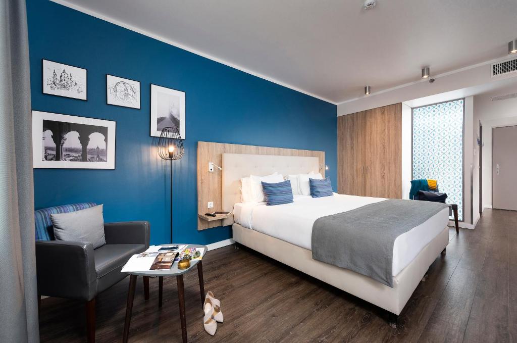 een slaapkamer met een groot bed en een stoel bij Three Corners Lifestyle Hotel in Boedapest