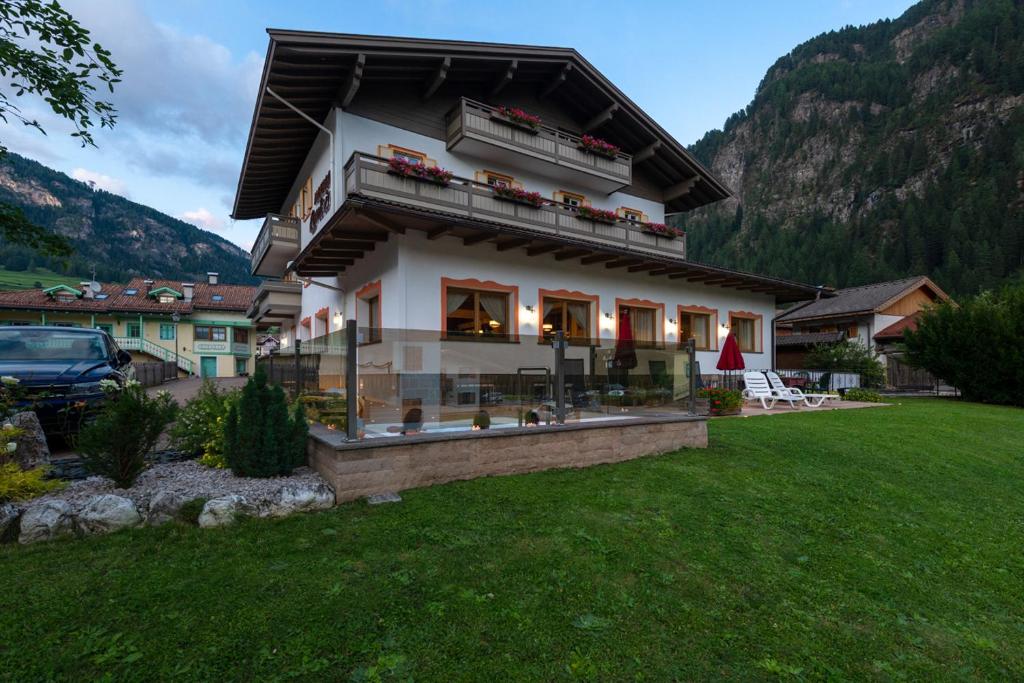 una casa in un campo con una montagna di Albergo Contrin a Campitello