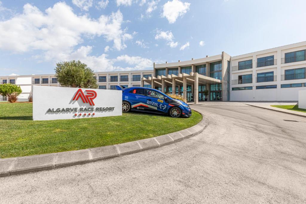 a car parked in front of a large building at Algarve Race Resort - Hotel in Montes de Cima