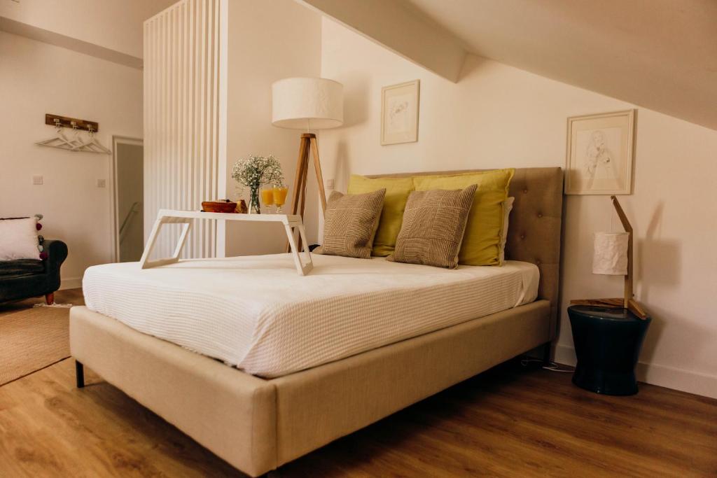 a bedroom with a bed with white sheets and yellow pillows at Amoreira in Setúbal