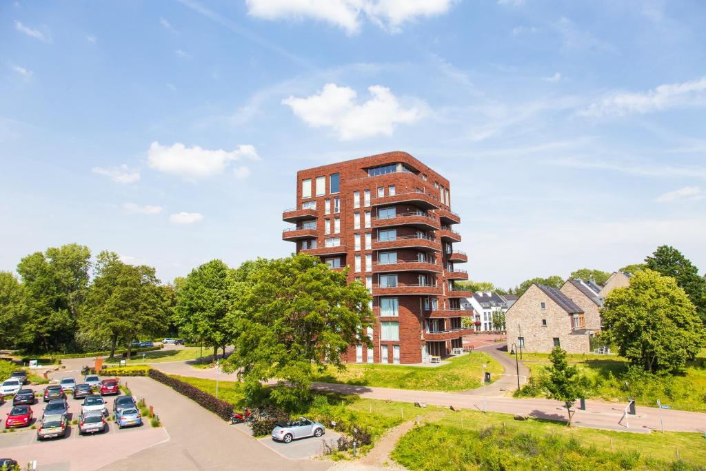 ein Apartmenthaus mit Autos auf einem Parkplatz in der Unterkunft Dormio Hotel De Prins van Oranje in Maastricht