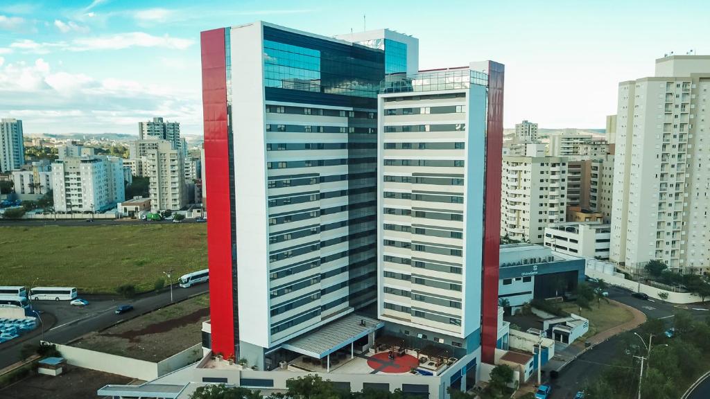 a tall building with red and white in a city at TRYP By Wyndham Ribeirão Preto in Ribeirão Preto