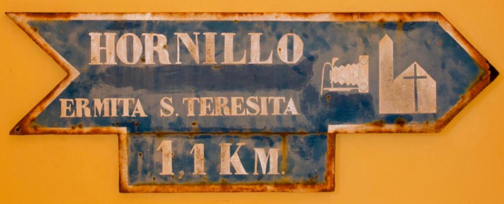 un panneau bleu sur un mur jaune dans l'établissement Refugio El Hornillo, à San Pedro