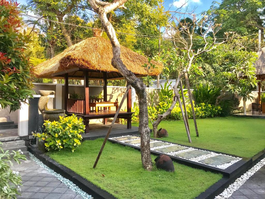 a garden with a hut with two animals laying on the grass at The Celuk Homestay in Jimbaran