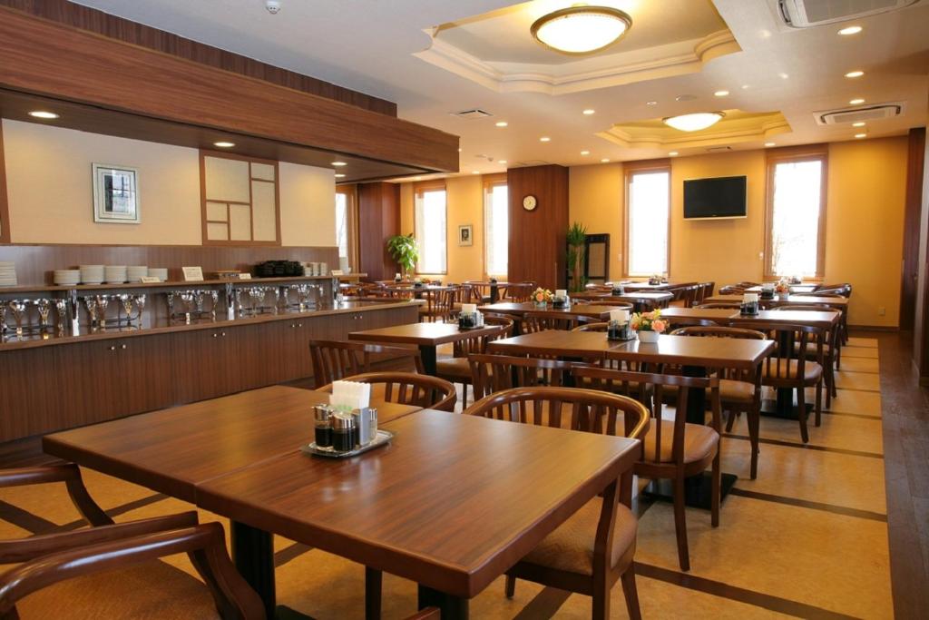 un restaurant avec des tables et des chaises en bois ainsi qu'un bar dans l'établissement Hotel Route-inn Koriyama Inter, à Koriyama