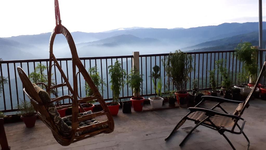 een stoel en potplanten op een balkon met uitzicht bij The River View Homestay in Kurseong