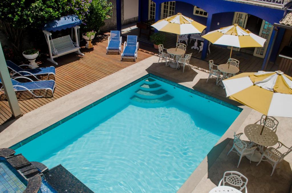 an overhead view of a swimming pool with chairs and umbrellas at Pousada Portal do Mar in Cabo Frio