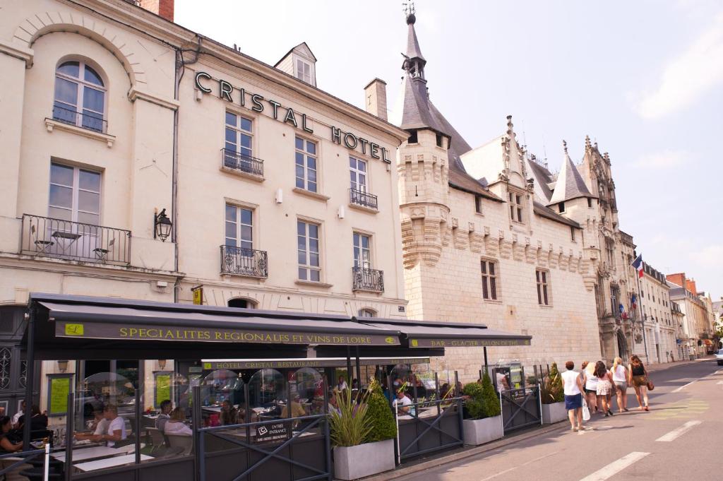 eine Gruppe von Menschen, die vor einem Gebäude spazieren in der Unterkunft Cristal Hôtel Restaurant - Logis Hotels in Saumur