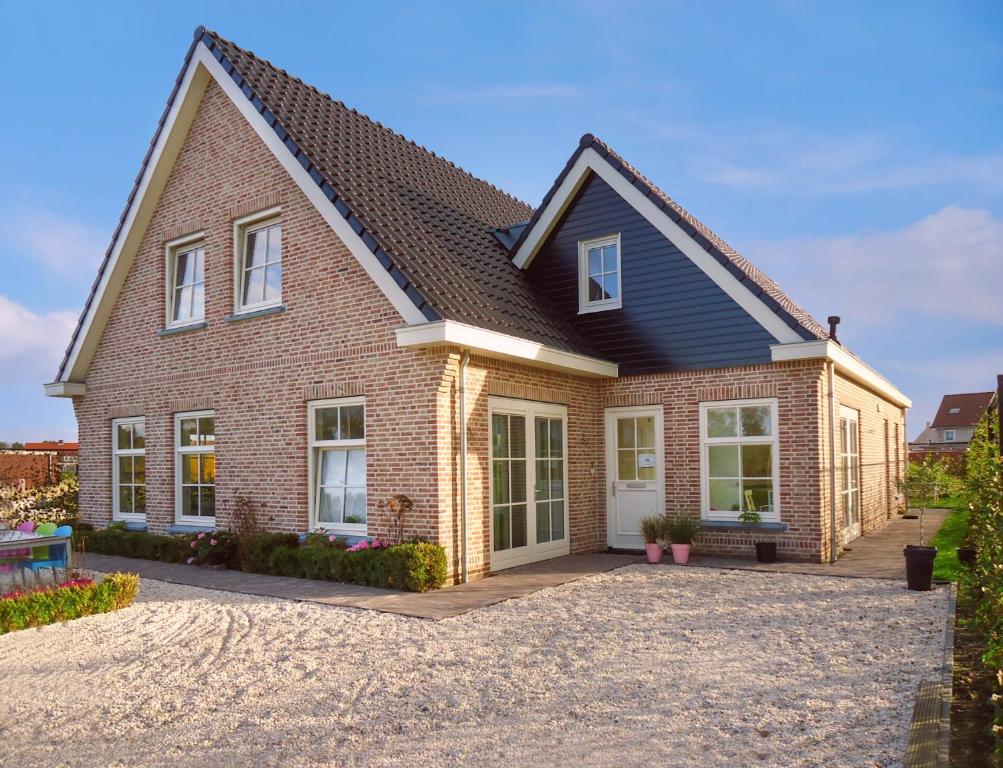 a red brick house with a black roof at Luxe vakantiewoning Zeeduinsepoort met Sauna in Oostkapelle