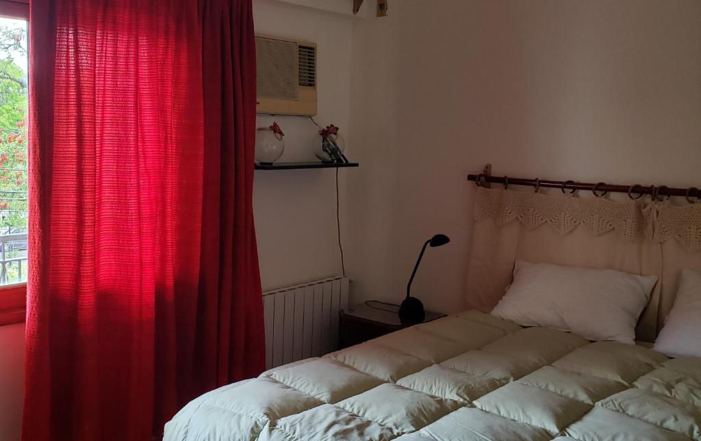 1 dormitorio con 1 cama con cortina roja y ventana en La casa del Paseo, en Salta