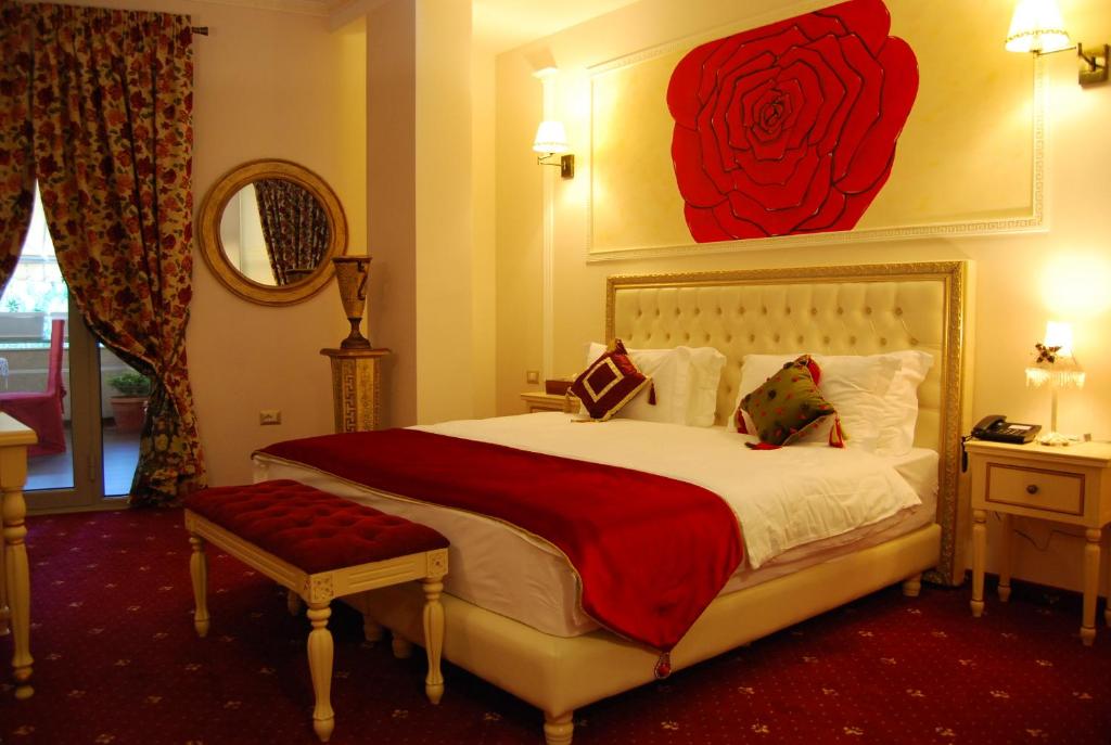 een slaapkamer met een groot bed met een rood rozenschilderij aan de muur bij 2 KITARRAT Boutique Hotel & SPA in Durrës