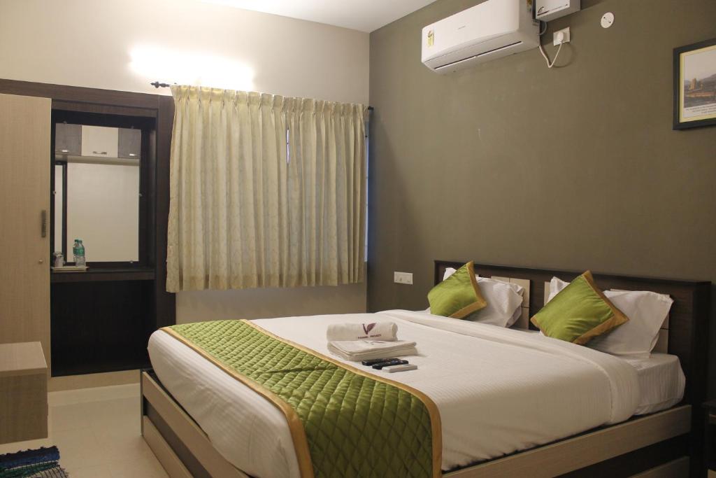 1 dormitorio con 1 cama grande con almohadas verdes en Viswa Residency by Azalea, en Madurai