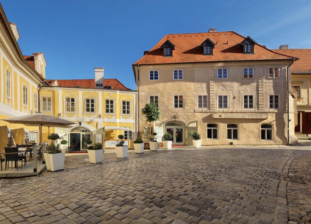 Bellevue Hotel Český Krumlov في تشيسكي كروملوف: شارع بالحصى في مدينة بها مباني