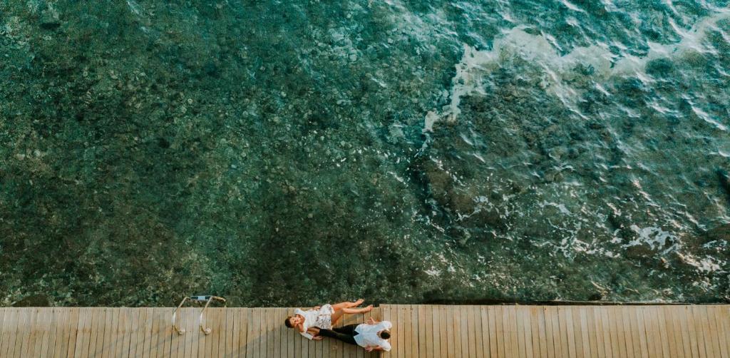 een persoon die op een muur staat en naar de oceaan kijkt bij Pefkaki Boutique Hotel Loutraki in Loutraki