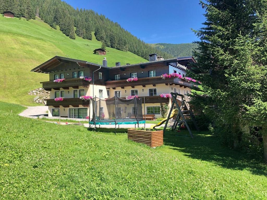 une grande maison sur une colline avec une aire de jeux dans l'établissement Jenneweinhof, à Tux