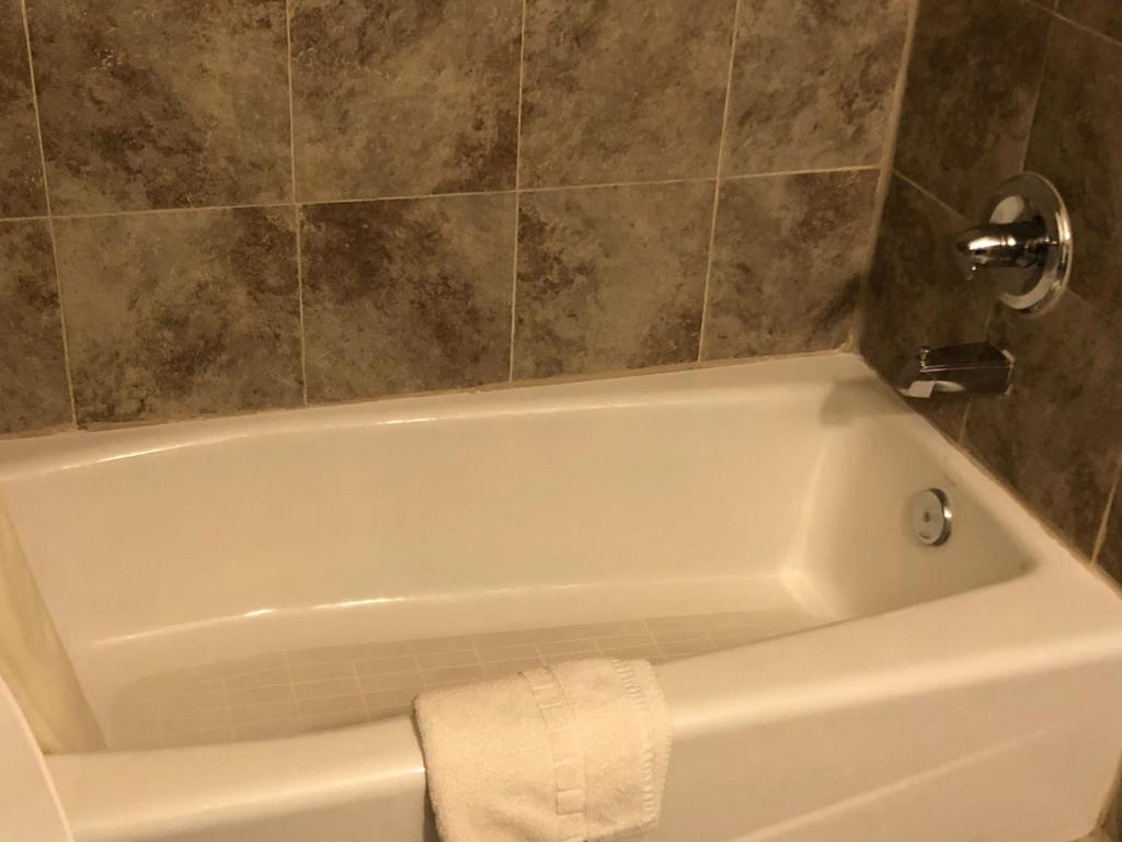 eine weiße Badewanne im Bad mit einer Kachelwand in der Unterkunft Economy Inn Alamogordo in Alamogordo