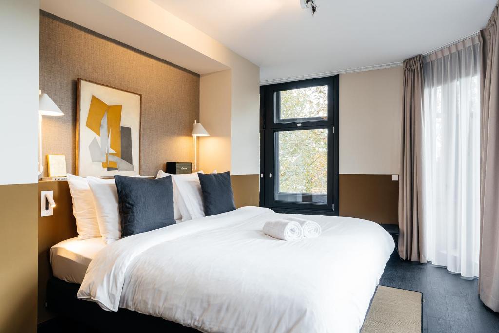 a bedroom with a large white bed and a window at The Hunfeld in Utrecht