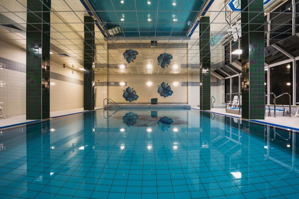 una gran piscina con azulejos azules en el suelo en Olymp II, en Kołobrzeg