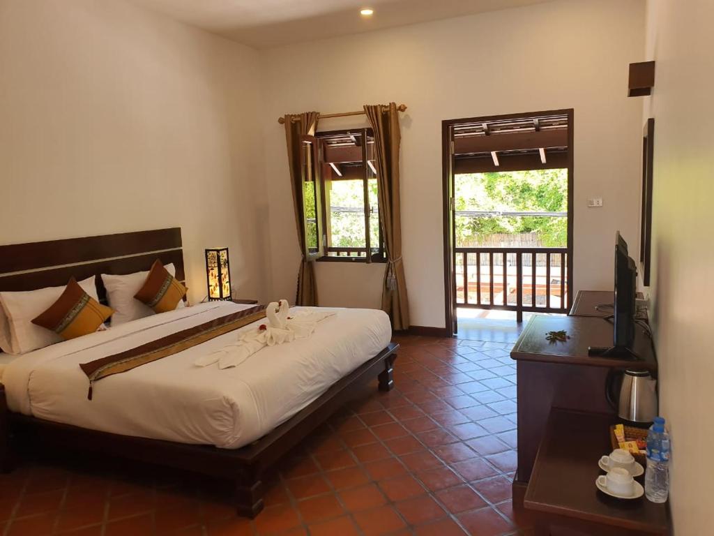 1 dormitorio con 1 cama y TV en Villa Chitchareune 2, en Luang Prabang