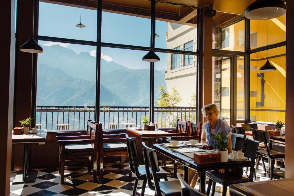 une personne assise à une table dans un restaurant avec vue dans l'établissement Mountain View Station, à Sa Pa