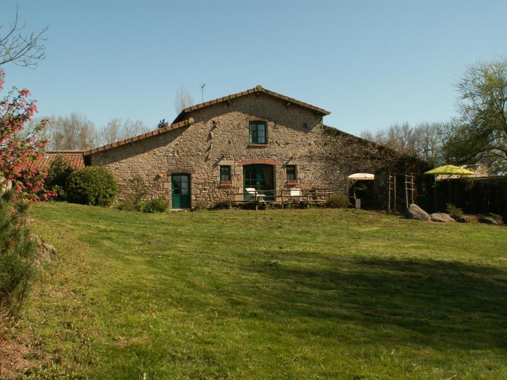 una vecchia casa in pietra con un prato davanti di La Trainelière a Les Épesses