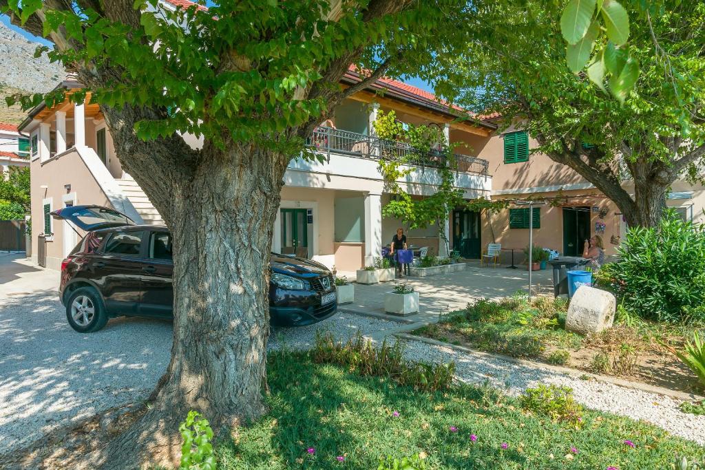 un'auto parcheggiata di fronte a una casa con un albero di Apartments Roko a Duće