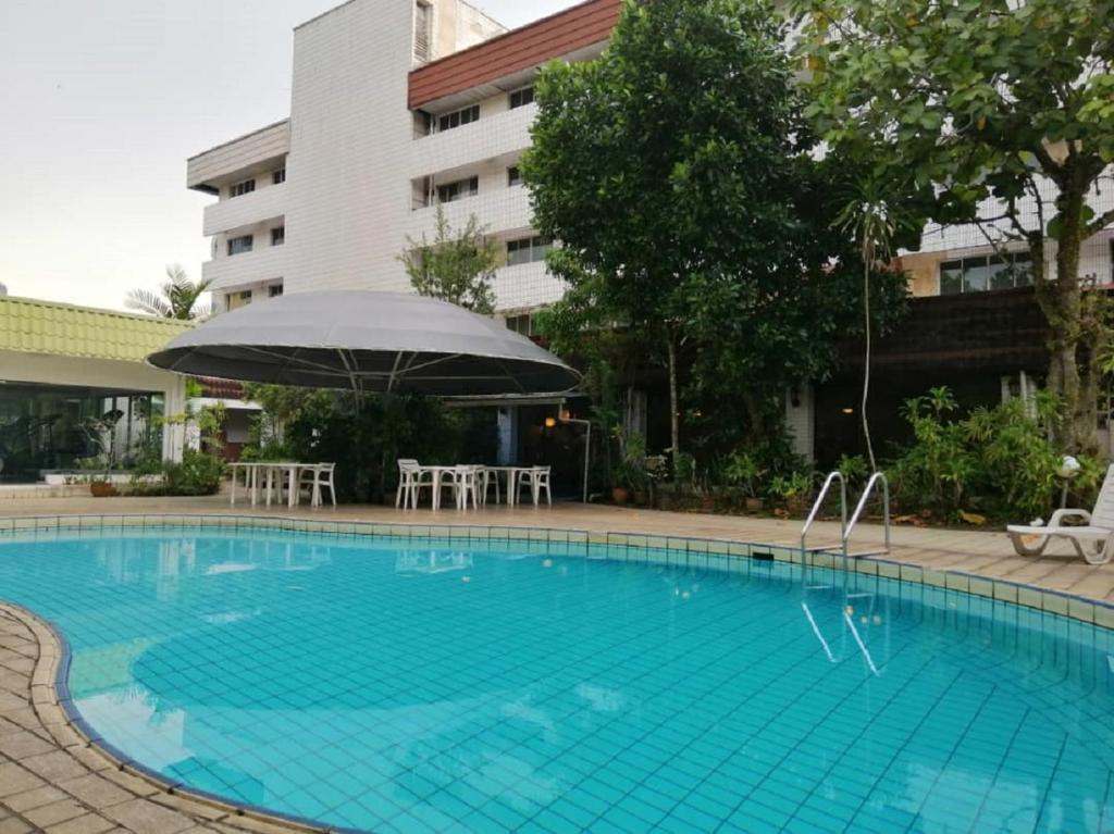 ein Pool mit Sonnenschirm und Stühlen sowie ein Gebäude in der Unterkunft Terrace Hotel in Bandar Seri Begawan