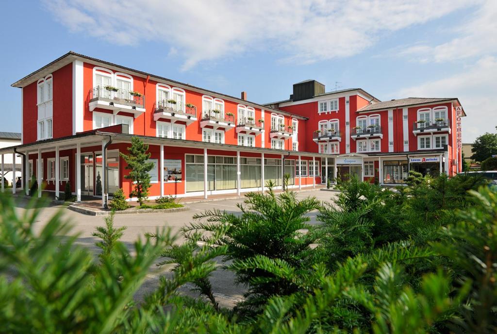 um grande edifício vermelho com árvores em frente em Johannesbad Hotel Füssinger Hof em Bad Füssing