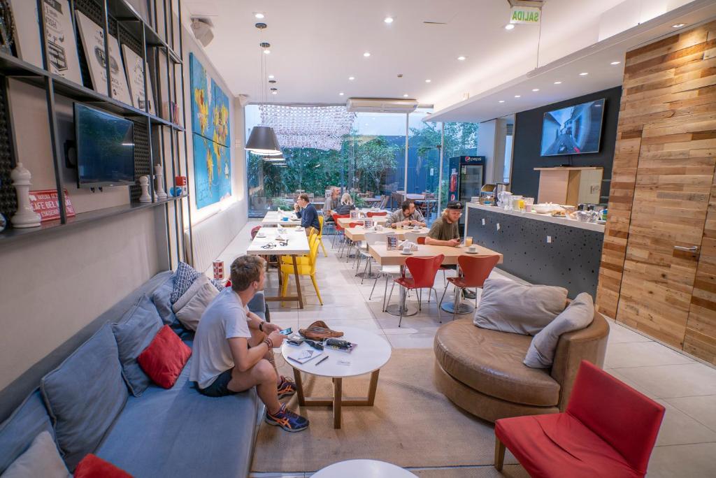 ein Restaurant mit Leuten, die auf Sofas und Tischen sitzen in der Unterkunft America Del Sur Hostel Buenos Aires in Buenos Aires