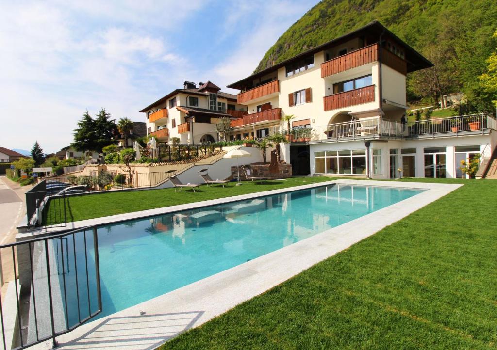 una casa con piscina di fronte a un edificio di Hotel Römerrast a Caldaro