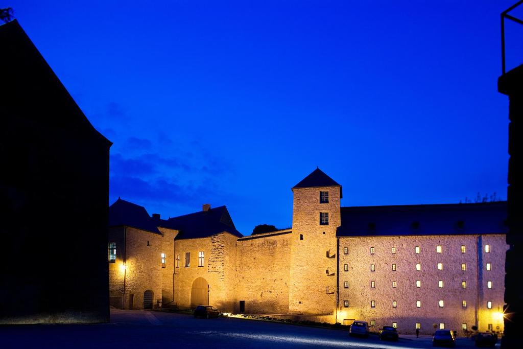 un gran castillo iluminado por la noche en Hôtel Le Château Fort de Sedan, en Sedan