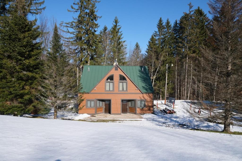 una casa arancione con un tetto verde nella neve di Ski in/out Spruce Glen Townhomes on Great Eastern Trail a Killington