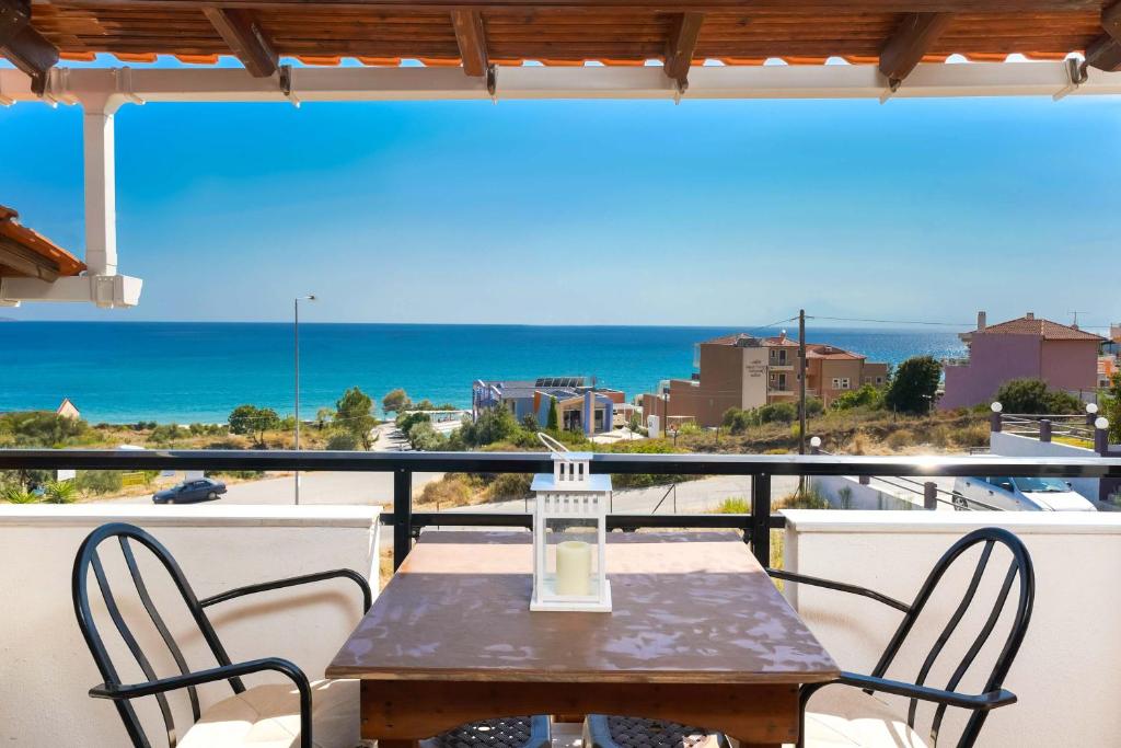 una mesa y sillas en un balcón con vistas al océano en Villa Golden Nest, en Limenaria