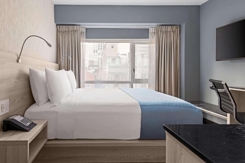 een hotelkamer met een groot bed en een raam bij Wingate by Wyndham New York Midtown South/5th Ave in New York