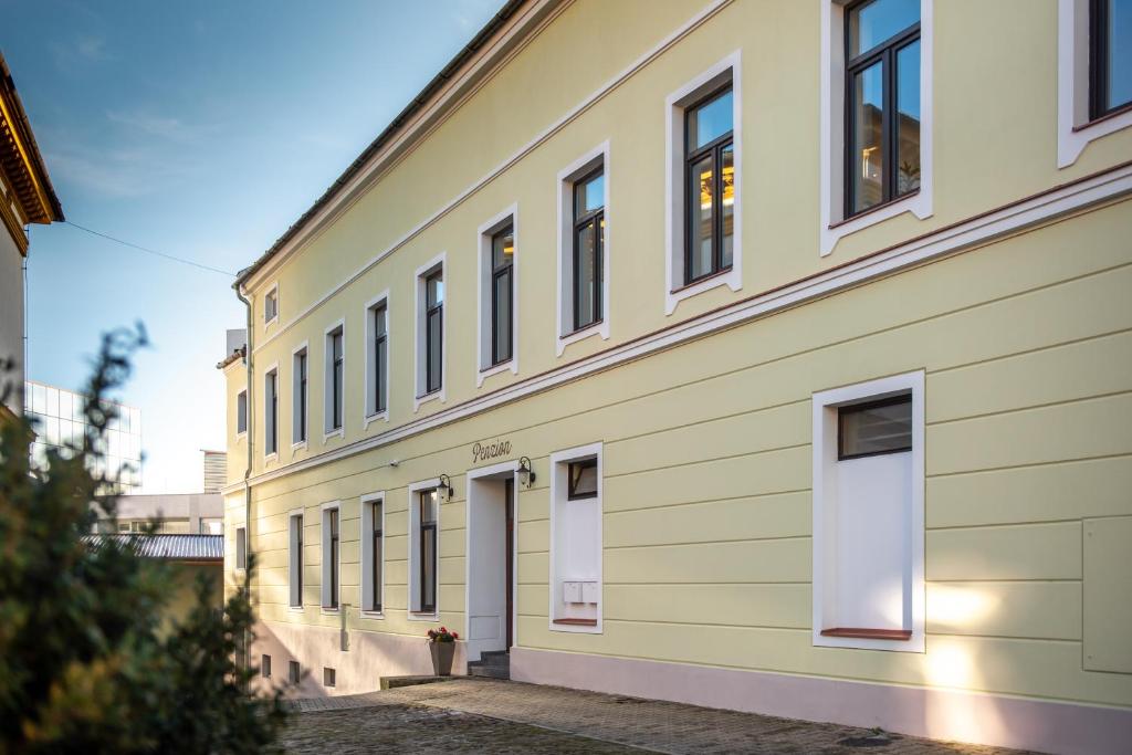 un edificio amarillo con puertas y ventanas blancas en Penzion Stará pošta, en Frýdek-Místek