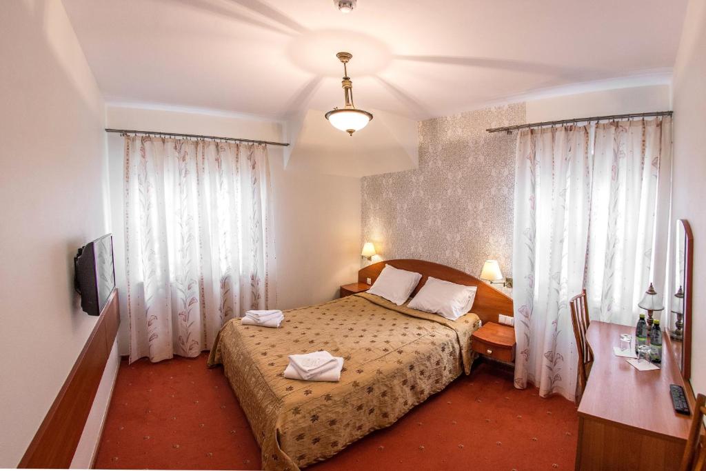 Schlafzimmer mit einem Bett, einem Schreibtisch und Vorhängen in der Unterkunft Hotel Karczówka in Kielce