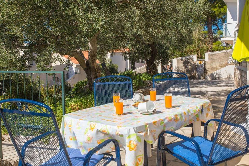 a table with blue chairs and a table with orange juice at Apartmani Stipan in Brela