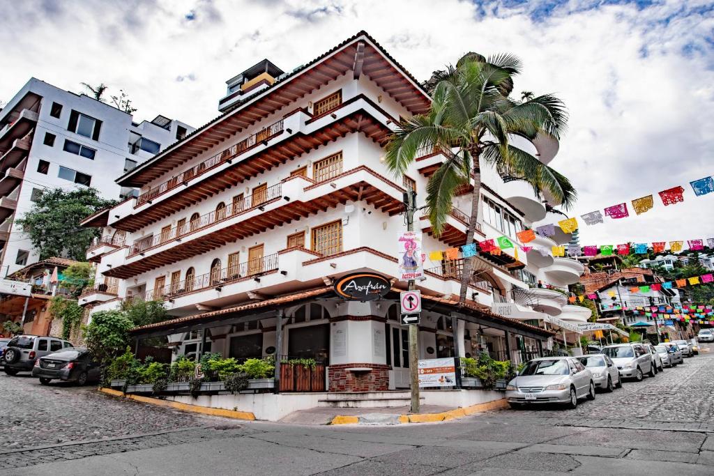 een gebouw met een palmboom voor een straat bij Olas Altas Suites Departamentos in Puerto Vallarta