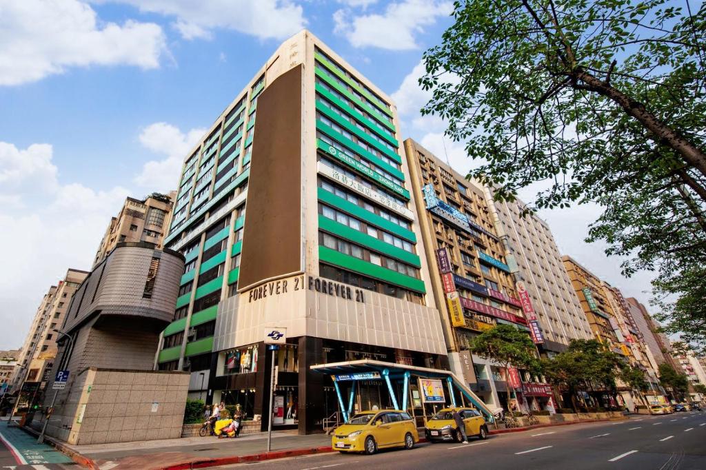 Un grand bâtiment avec des voitures garées devant lui dans l'établissement Green World ZhongXiao, à Taipei