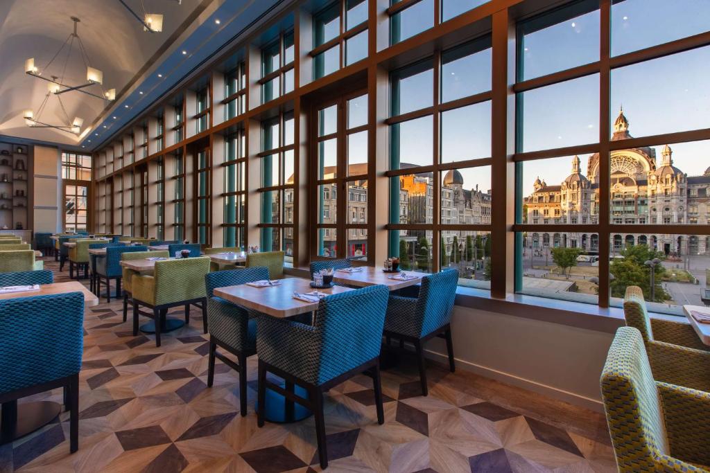 een restaurant met tafels en stoelen en grote ramen bij Radisson Blu Hotel, Antwerp City Centre in Antwerpen