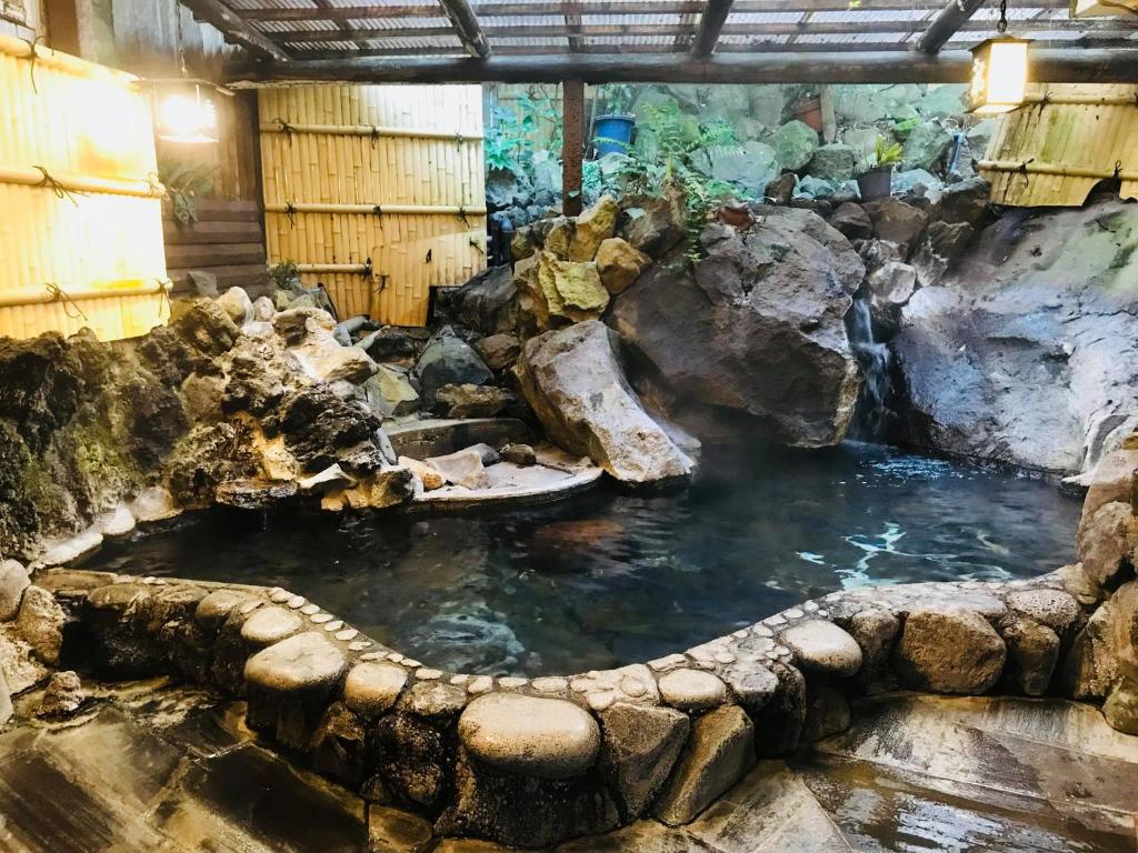 una grande piscina d'acqua in una stanza con rocce di Tsukinoya a Hakone