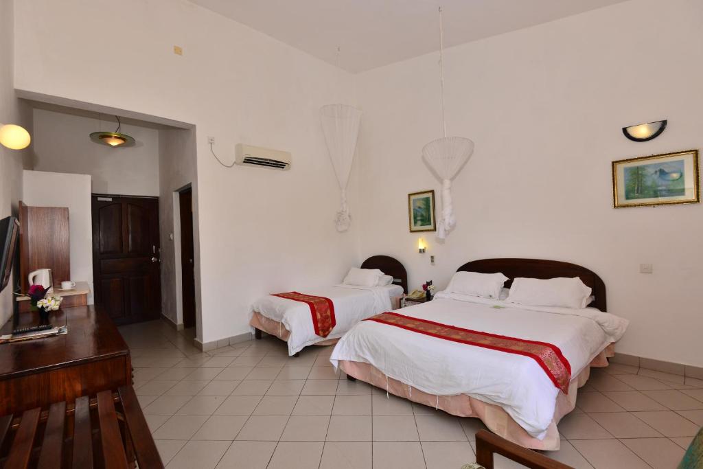 una camera d'albergo con due letti e una televisione di Baobab Holiday Resort a Bamburi