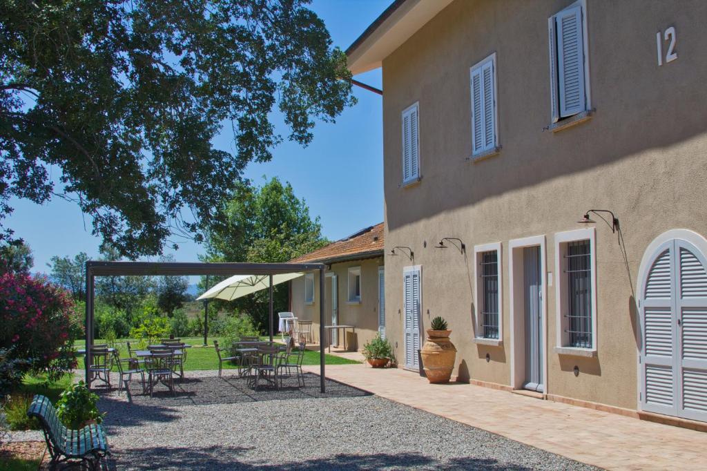 un patio con mesas y sillas junto a un edificio en Agriturismo Poderedodici, en Orbetello