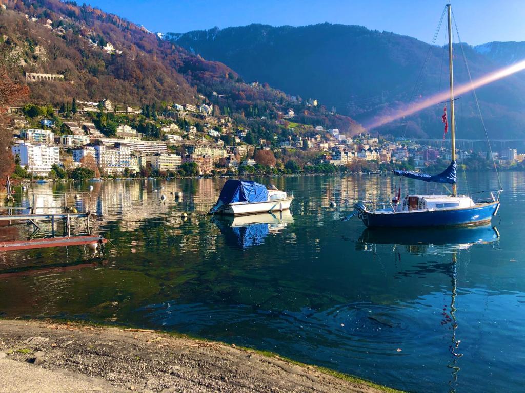 two boats are docked on a lake with a city at B&B Guest House Du Lac in Montreux