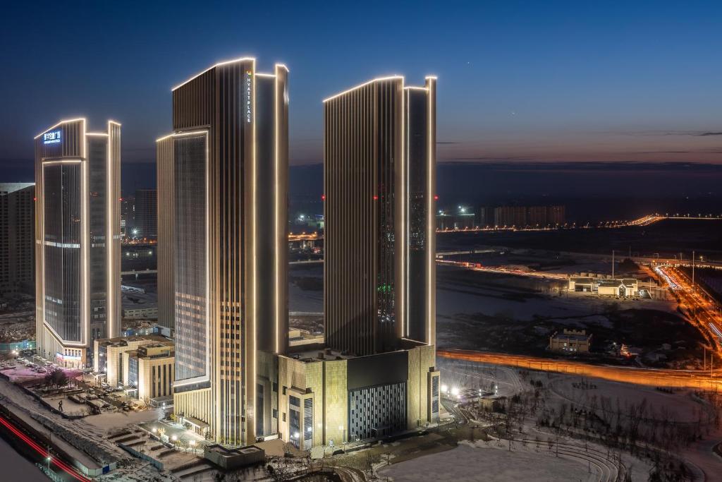 um grupo de edifícios altos em uma cidade à noite em Hyatt Place Changchun Jingyue em Changchun