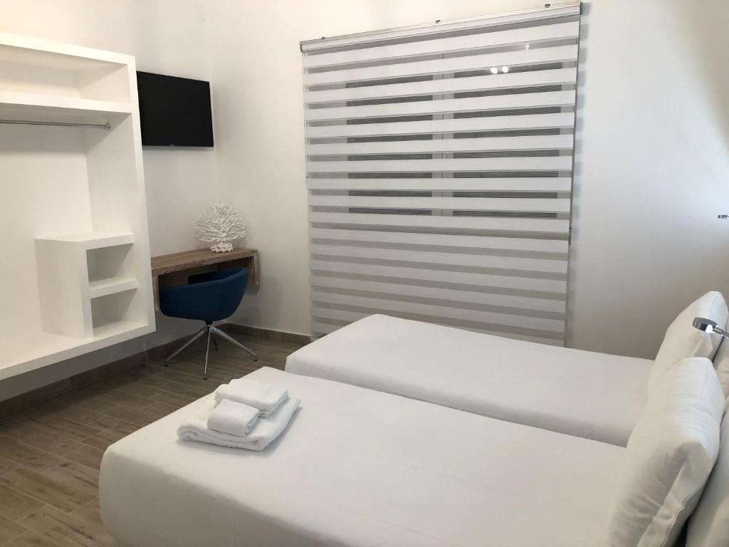 Cette chambre comprend deux lits, une table et une chaise. dans l'établissement B&B Villa S.Anna, à Bari