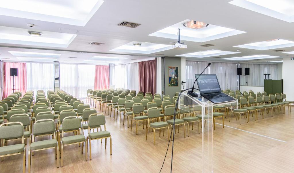 ein Zimmer mit Stühlen und einem Laptop auf einem Podium in der Unterkunft Hotel Metropol in Larisa