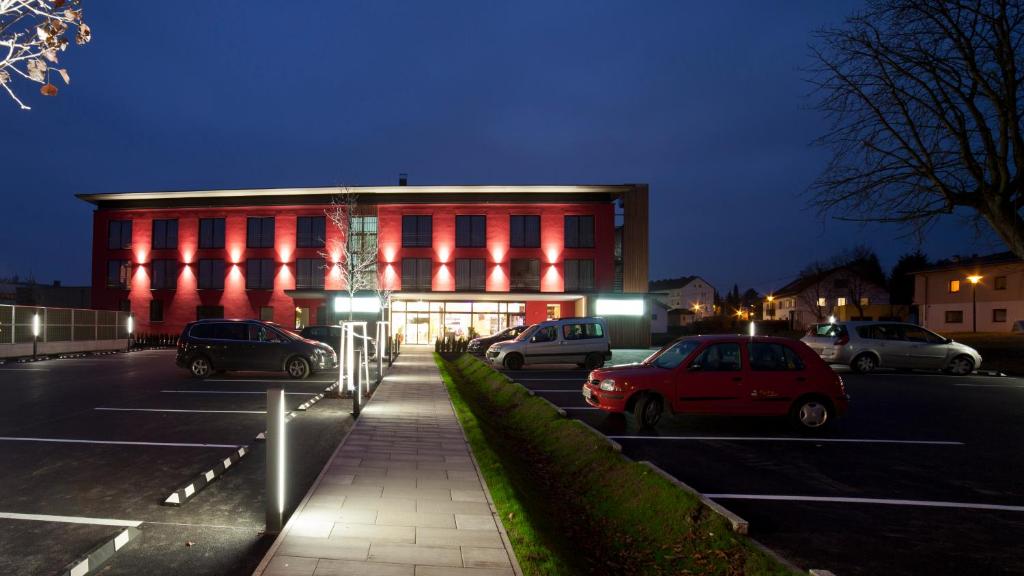 een rood gebouw met auto's geparkeerd op een parkeerplaats bij Hotel Wallern Garni in Wallern an der Trattnach